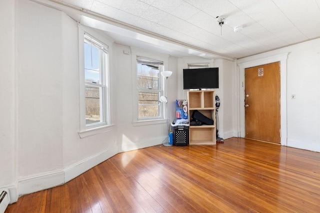 unfurnished room with a baseboard heating unit and hardwood / wood-style floors