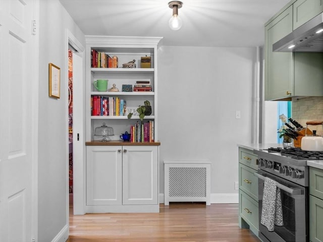 kitchen featuring green cabinets, stainless steel range, exhaust hood, and light wood-style floors