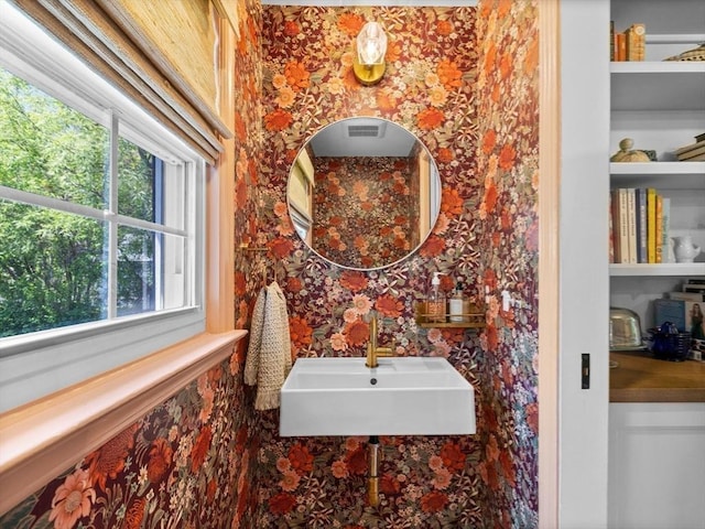 bathroom with a sink and wallpapered walls