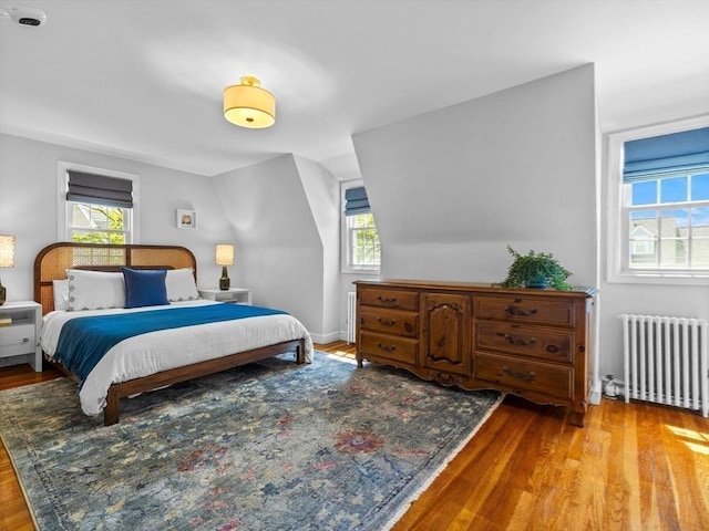 bedroom featuring radiator, wood finished floors, and vaulted ceiling