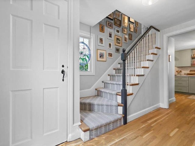 foyer featuring stairs, light wood-style flooring, and baseboards