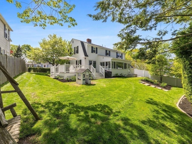 rear view of house with a chimney, a wooden deck, and a sunroom
