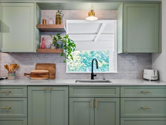 kitchen with green cabinetry, a sink, open shelves, and backsplash