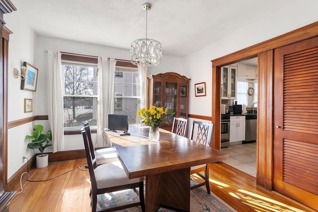 dining area featuring sink, a notable chandelier, and light hardwood / wood-style flooring