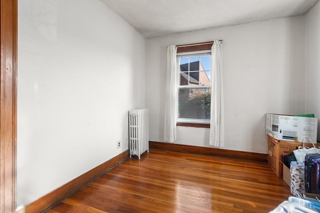 empty room with dark hardwood / wood-style floors and radiator