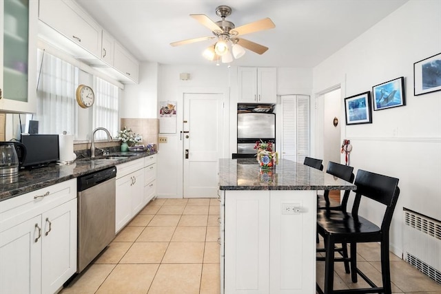 kitchen with sink, a breakfast bar area, refrigerator, stainless steel dishwasher, and radiator