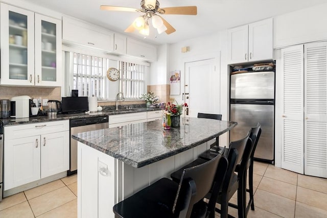 kitchen featuring light tile patterned floors, appliances with stainless steel finishes, sink, and dark stone counters