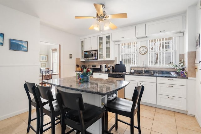 kitchen with appliances with stainless steel finishes, a breakfast bar, sink, and white cabinets