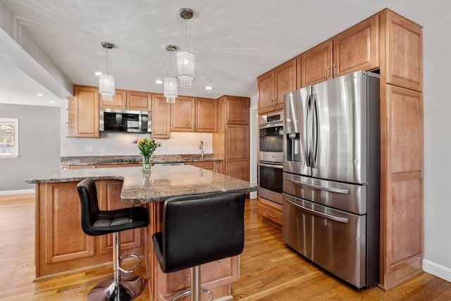 kitchen with light stone counters, appliances with stainless steel finishes, light wood-type flooring, and baseboards