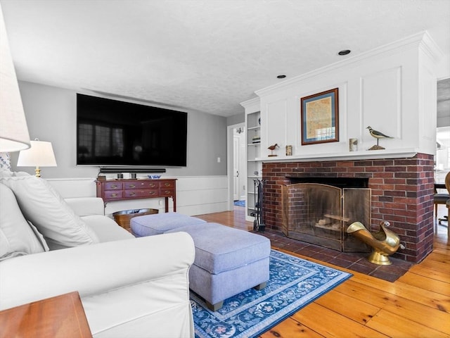 living room featuring wainscoting, a fireplace, and hardwood / wood-style floors