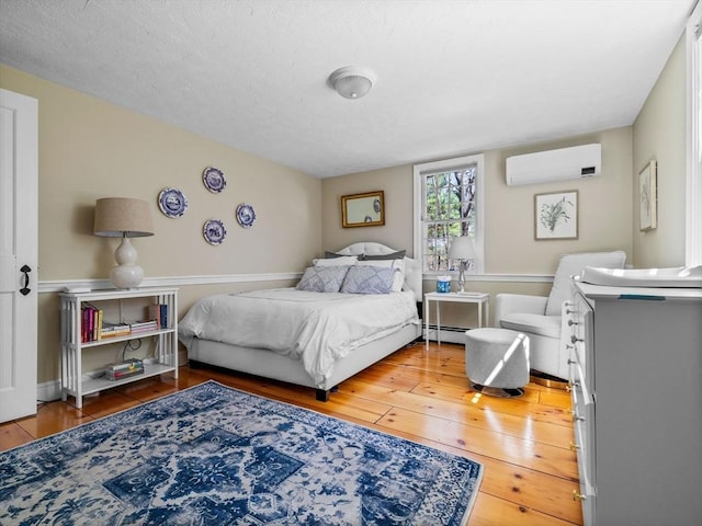 bedroom featuring a wall mounted AC, a baseboard heating unit, and hardwood / wood-style flooring