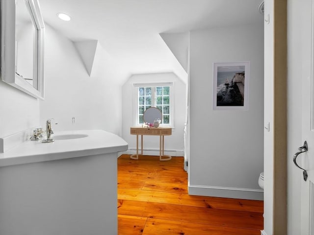 bathroom with lofted ceiling, toilet, baseboards, baseboard heating, and hardwood / wood-style flooring