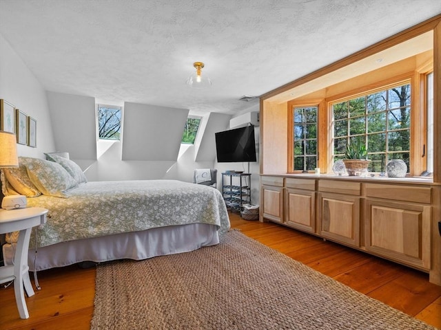 bedroom with a textured ceiling, visible vents, and hardwood / wood-style flooring