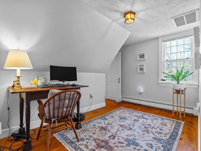 office with visible vents, vaulted ceiling, wood finished floors, baseboards, and a baseboard heating unit