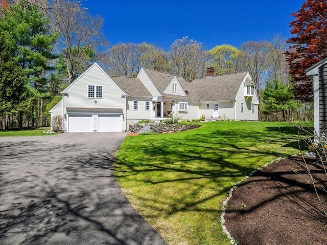 view of front of home with a garage, a chimney, a front lawn, and aphalt driveway