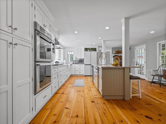 kitchen featuring double oven, light wood finished floors, and white cabinetry