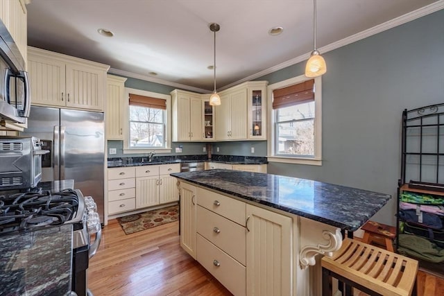 kitchen featuring pendant lighting, crown molding, a breakfast bar area, appliances with stainless steel finishes, and cream cabinets