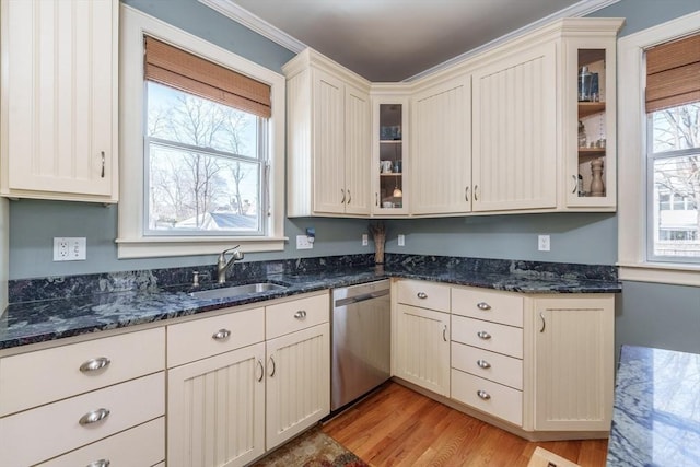 kitchen with sink, dark stone counters, ornamental molding, stainless steel dishwasher, and light hardwood / wood-style flooring