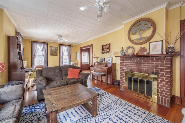 living room featuring crown molding, ceiling fan, wood-type flooring, and a brick fireplace