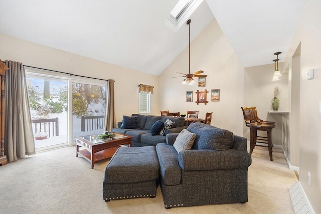 carpeted living room featuring a skylight, high vaulted ceiling, and ceiling fan