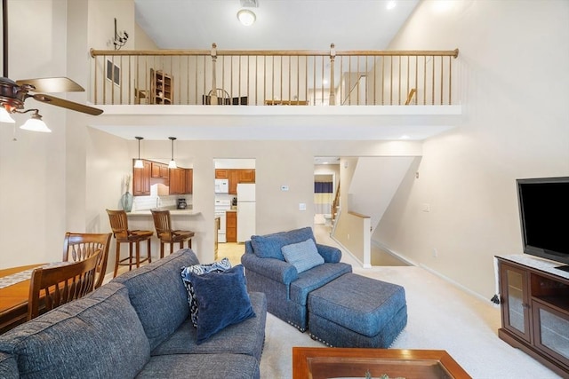 carpeted living room with ceiling fan and a high ceiling