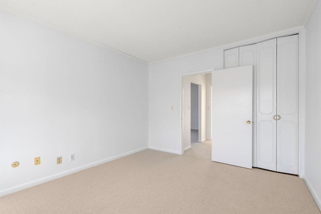 unfurnished bedroom featuring light carpet, ornamental molding, a closet, and baseboards