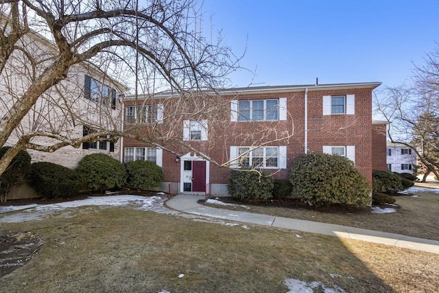 multi unit property featuring brick siding and a front lawn