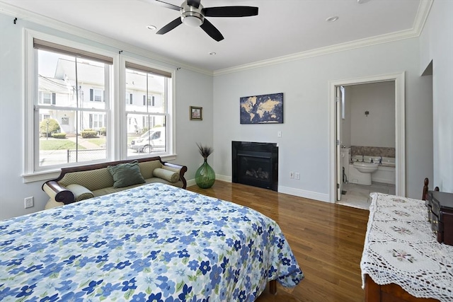 bedroom featuring multiple windows, wood finished floors, ornamental molding, baseboards, and ensuite bath