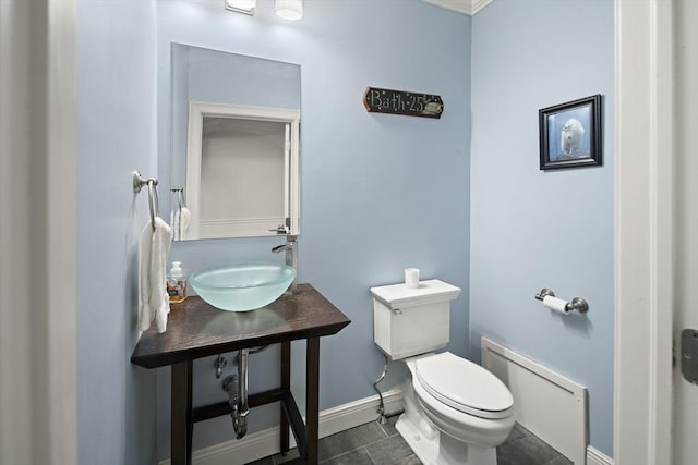 half bathroom with toilet, a sink, and baseboards