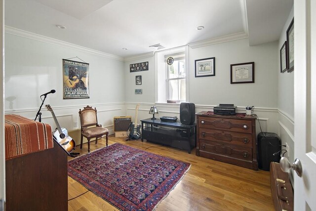 office space with crown molding, wood finished floors, and a wainscoted wall
