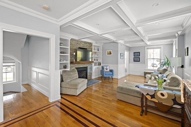 living room with a decorative wall, hardwood / wood-style flooring, a fireplace, built in shelves, and arched walkways