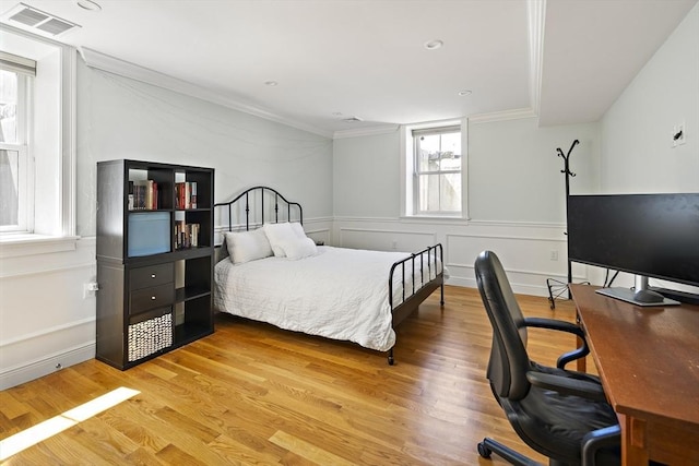 bedroom featuring wood finished floors, ornamental molding, and an office area