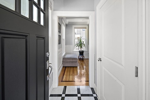 entrance foyer with a decorative wall, wainscoting, and light wood-style flooring