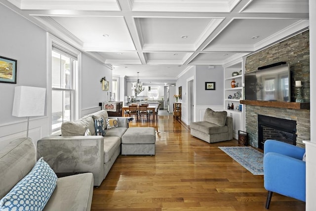 living area featuring plenty of natural light, wood finished floors, a fireplace, beamed ceiling, and ornamental molding