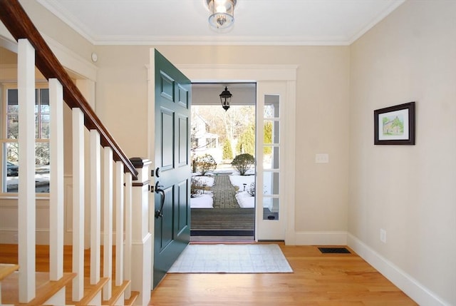 entrance foyer featuring visible vents, stairway, ornamental molding, wood finished floors, and baseboards