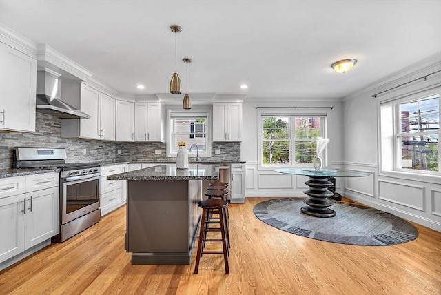 3 Lowell St Unit 1, Waltham, MA 02453 - kitchen featuring gas stove, wall chimney range hood, healthy amount of natural light, a kitchen bar, and crown molding