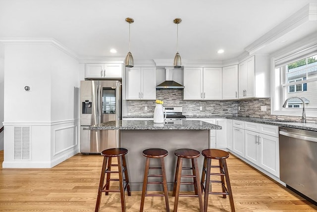 3 Lowell St Unit 1, Waltham, MA 02453 - kitchen featuring appliances with stainless steel finishes, wall chimney range hood, a breakfast bar area, a center island, and white cabinetry