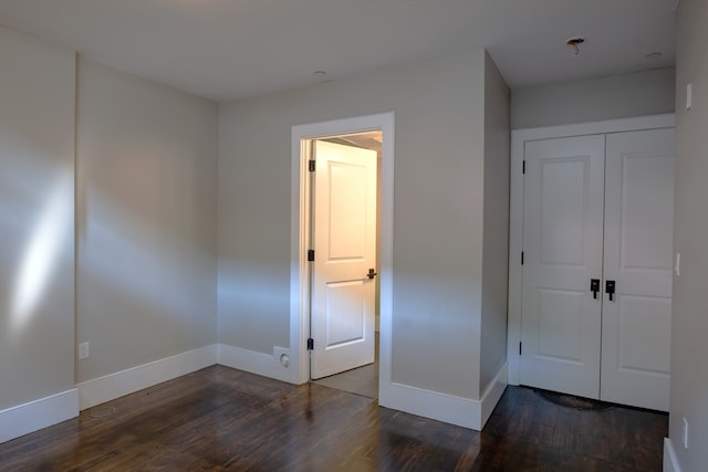 unfurnished bedroom featuring a closet and dark wood-type flooring