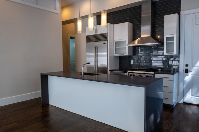 kitchen with wall chimney exhaust hood, stainless steel appliances, white cabinetry, and decorative light fixtures