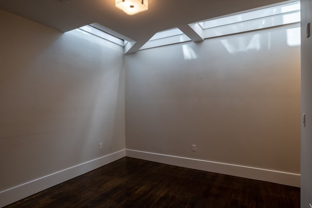 unfurnished room featuring dark wood-type flooring and a skylight