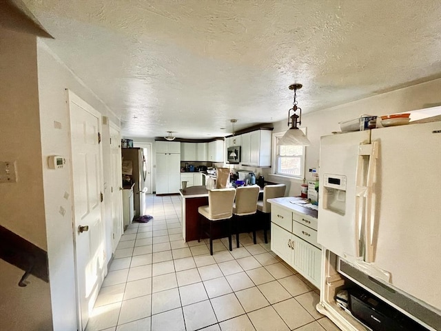 48 Grove, Plympton, MA 02367 - kitchen with white fridge with ice dispenser, light tile patterned floors, stainless steel microwave, white cabinets, and light countertops