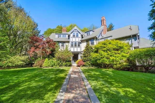 tudor home with a chimney and a front lawn