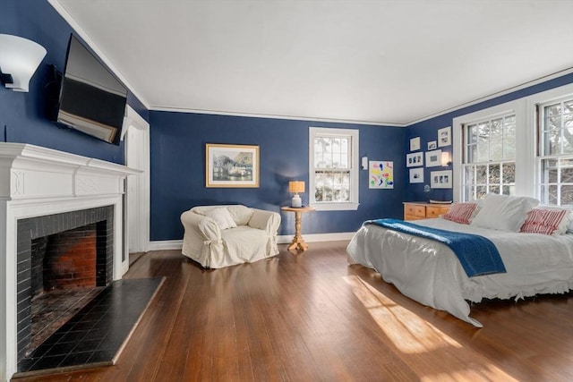 bedroom with ornamental molding, a fireplace, wood finished floors, and baseboards