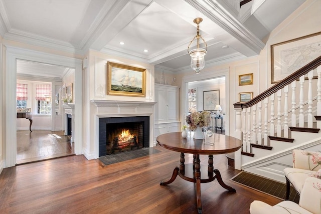 entrance foyer featuring stairway, a fireplace with flush hearth, ornamental molding, beamed ceiling, and hardwood / wood-style flooring