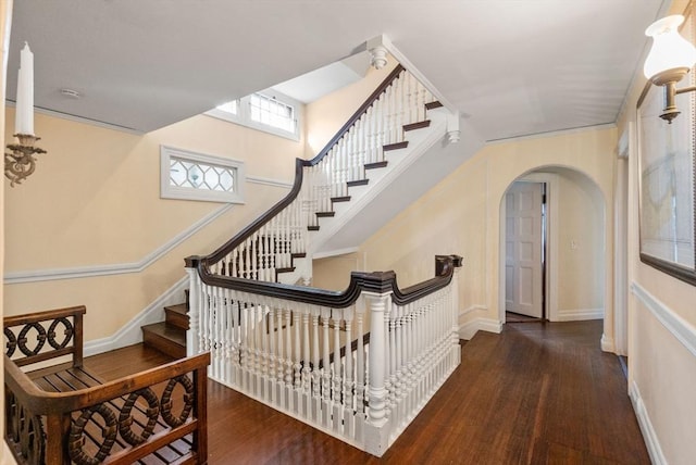 interior space with arched walkways, baseboards, and wood finished floors