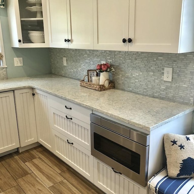 14 Highland St, Clinton, MA 01510 - kitchen with white cabinets, stainless steel microwave, glass insert cabinets, backsplash, and dark wood-style floors