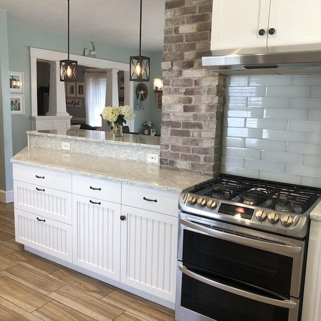14 Highland St, Clinton, MA 01510 - kitchen featuring range with two ovens, range hood, white cabinets, light stone countertops, and light wood-type flooring