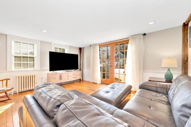 living area featuring radiator, light wood finished floors, recessed lighting, and french doors