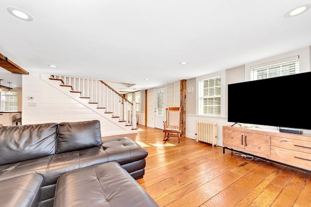 living room with light wood-type flooring, recessed lighting, radiator heating unit, and stairs