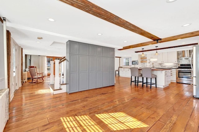 unfurnished living room with light wood-style flooring, radiator heating unit, stairs, beam ceiling, and recessed lighting